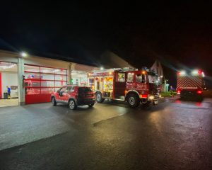 mehrere Feuerwehreinsatzfahrzeuge in der Dunkelheit vor einer hell erleuchteten Feuerwache