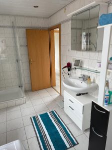 Tür eines Badezimmers, Dusche und Waschbecken mit Spiegel