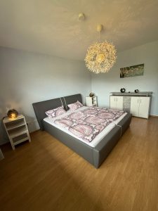 Schlafzimmer mit Bett und Lampe, Kommode, Nattischschrank