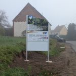 Ortseingangsschild von Güdesweiler, weißes Schild mit Foto eines Weihers ; Herzlich Willkommen in Güdesweiler, Schild, das die deutsch-französische Freundschaft zwischen den Partnergemeinden Oberthal und Moyenmoutier beschreibt. Weiteres weißes Schild.