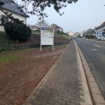 Ortseingangsschild von Steinberg-Deckenhardt, weißes Schild mit Foto mit Blick über Steinberg-Deckenhardt; Herzlich Willkommen in Steinberg-Deckenhardt, Schild, das die deutsch-französische Freundschaft zwischen den Partnergemeinden Oberthal und Moyenmoutier beschreibt. Weiteres weißes Schild.