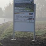 Ortseingangsschild von Steinberg-Deckenhardt, weißes Schild mit Foto mit Blick über Steinberg-Deckenhardt; Herzlich Willkommen in Steinberg-Deckenhardt, Schild, das die deutsch-französische Freundschaft zwischen den Partnergemeinden Oberthal und Moyenmoutier beschreibt. Weiteres weißes Schild.